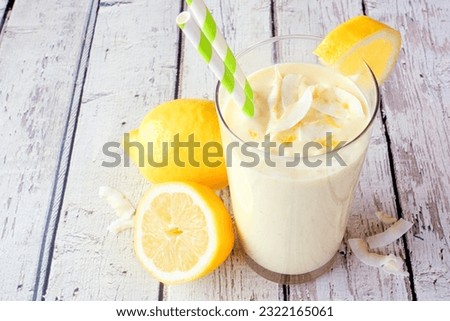 Summer lemon coconut smoothie. Close up table scene with a white wood background.