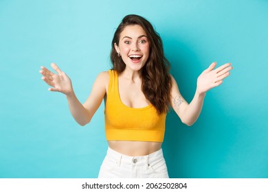 Summer And Lifestyle Concept. Beautiful Woman Look Surprised And Happy To See You, Spread Hands Sideways And Smiling Happy, Greeting Person, Standing Over Blue Background