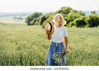 Summer Lifestyle Concept. Trendy adult woman in stylish summer dress feeling free in the field with wild flowers in sunshine.