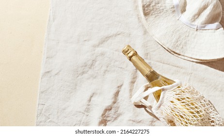 Summer Lifestyle Flat Lay With Bottle White Wine, Sun Hat On Beach Towel As Background. Summer Beach Concept Holiday And Party, Romance Picnic With Champagne Sparkling Wine. Top View, Sunlight