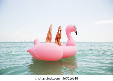Summer lifestyle funny  image of two pretty girls friends having fun on air mattress in the ocean. Doing yoga and having fun. Legs up in the air. Positive emotions, bright colors 