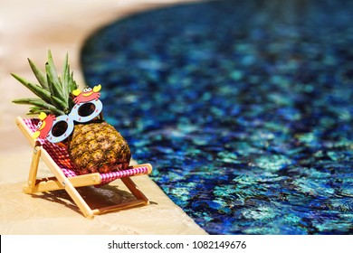 Summer Lifestyle Image Of Young Pretty Girl-pineapple Lying On Sun Chaise Near The Turquoise Swimming Pool. Wearing Funny Sunglasses. Rest In Paradise. Tropical Summer Vacation Concept. Sunbathing