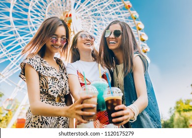 Summer lifestyle portrait multiracial women enjoy nice day, holding glasses of milkshakes. Happy friends inin front of ferris wheel. Best friends girls having fun, joy. Lifestyle. Asian, jewess and - Powered by Shutterstock