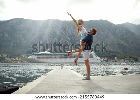Summer love. Happy couple on dock. Man holding woman, she is enjoying freedom. Travel, love, fun, togetherness concept.