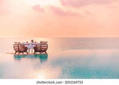 Summer Love And Romance Table Set-up For A Romantic Dinner Meal With Infinity Pool Reflection Chairs Under Sunset Sky And Sea In The Background. Luxury Destination Dining, Romantic Dinner For Couples