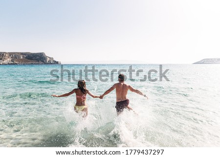 Summer love story on the beach. A couple in love running in the aqua blue sea and holding hands. Relax on the seaside