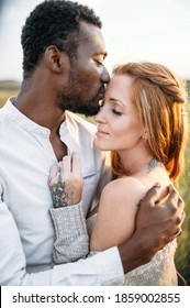 Summer love story on the meadow. An african american man in hugging charming young woman with care and awe