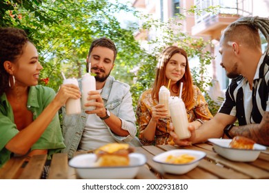 Summer  milkshake. Young friends celebrating summer and drinking milkshakes in a cafe. People, lifestyle, lunch, party, relax concept. - Powered by Shutterstock