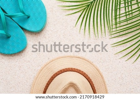 Summer minimalist mockup template on a sand background with straw hat, flipflop, palm tree and sand. Tropical vacation concept.