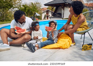 Summer moments of a family by the poolside. The parents, along with their children, a boy and a girl, come together to savor the delights of a refreshing watermelon feast.  - Powered by Shutterstock