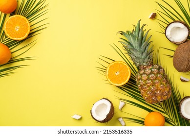 Summer mood concept. Top view photo of tropical fruits cracked coconuts pineapple cut oranges and palm leaves on isolated yellow background with empty space