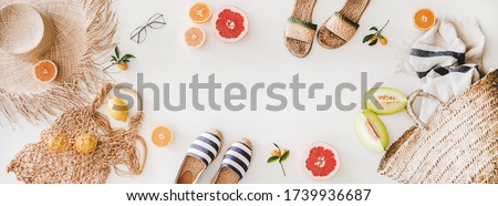 Summer mood layout. Flat-lay of summer natural espadrillas and sandals, straw sunhat, beach rafia and net bag, beach towel, sunglasses and fresh fruit over white plain background, top view, copy space