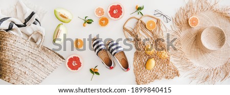 Summer mood layout. Flat-lay of summer natural espadrillas, straw sunhat, beach rafia and net bag, beach towel, sunglasses and fresh fruit over white plain background, top view Foto d'archivio © 