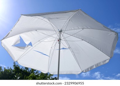 Summer morning in Western Europe. Wind-torn parasol is now a parasol with vents and always usable, no need to take it to the landfill and increase the waste pile - Powered by Shutterstock