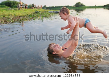 In the summer, mother and son swimming in the river