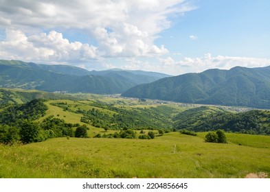 Summer mountain landscape with green rolling hills and the village in the valley in to the distance. Kolochava Transcarpathia, Carpathian Mountains, Ukraine 