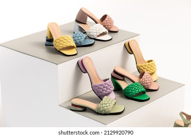 Summer multi-colored sandals with a heel on the podium in the form of steps in the studio on a white