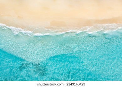 Summer nature landscape. Aerial view of sandy beach and ocean with waves. Beautiful tropical  island, white empty beach and sea waves seen from above, top aerial view. Tranquil, relaxing scenic