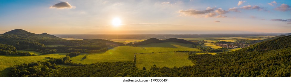 Summer Nature Scenery At Sunset With Green Forests And Meadow And Blue Sky. Panoramic Aerial View On Hills With Orange Sun Shining Above Horizon With Copy Space.