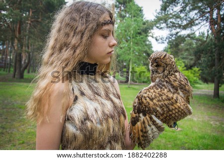 In summer, on a bright sunny day, a girl holding an owl on the ranch.