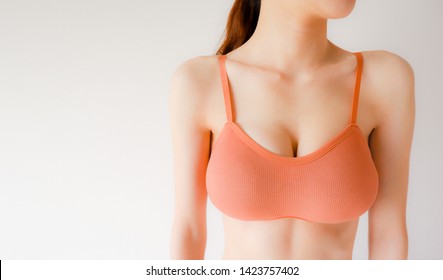 Summer Orange Bra. Beautiful Woman is Breast in Underwear Posing on Grey Background. Close Up Female Wearing Sport Bra (Sportswear). Fashion Fitness and Yoga Healthy Lifestyle.