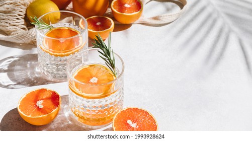 Summer orange cocktails with fresh citrus fruits. Hard seltzer, lemonade, refreshing drinks, low alcohol mocktails, summer party concept. Shadow and sunlight. Banner, flat lay, top view, copy space