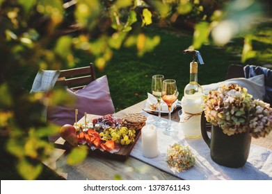 summer outdoor party table with white wine, cheese and ham plate with fruits. Garden festive table. 
