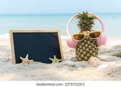 Summer in the party.  Hipster Pineapple Fashion in sunglass and listen music with blackboard on the sand beach beautiful blue sky background.  Fashion Summer Vacation Concept - Powered by Shutterstock