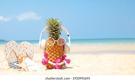 Summer party. Pineapple wearing sunglasses and listen to music with sunblock and sandal on beach and blue sky background. Tropical fashion. Summer Fashion on holiday concept.  - Powered by Shutterstock