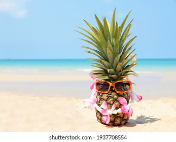 Summer party. Pineapple wearing sunglasses and listen to music on beach and blue sky background. Tropical fashion. Summer Fashion on holiday concept. 