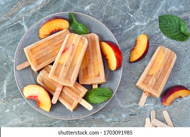 Summer Peach Yogurt Ice Pops On A Plate, Above View Table Scene Against A Dark Stone Background