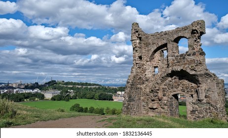 Summer Photo Of Saint Antony's Chapel Ruins In Holyrood Park. With Edinburgh Skyline And Famous Landmarks In The Background, Including Calton Hill And The City's Palace And Gardens In Scotland UK