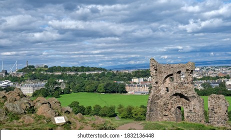 Summer Photo Of Saint Antony's Chapel Ruins In Holyrood Park. With Edinburgh Skyline And Famous Landmarks In The Background, Including Calton Hill And The City's Palace And Gardens In Scotland UK