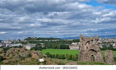 Summer Photo Of Saint Antony's Chapel Ruins In Holyrood Park. With Edinburgh Skyline And Famous Landmarks In The Background, Including Calton Hill And The City's Palace And Gardens In Scotland UK