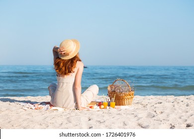 Summer - picnic by the sea. Girl in Hat and basket for a picnic with buns, apples and juice. 