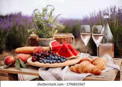 A Summer Picnic In A Lavender Field With Watermelon, Croissants And A Bottle Of Rose Wine And Two Glasses. Beautiful Rustic Decor. Gorizontal Format.