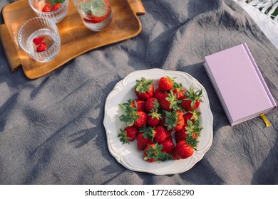 Summer Picnic On The Grass. Book, Fresh Strawberries, Refreshing Drinks On The Blanket. Top View, Lifestyle Concept.