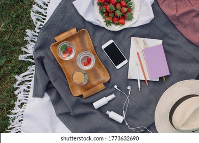 Summer Picnic On The Grass. Fresh Strawberries, Refreshing Lemonade,  Headphones, Mobile Phone, Diary, Hat On The Blanket. Top View, Lifestyle Concept.