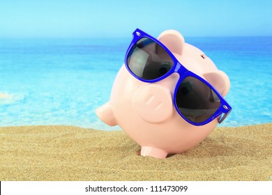 Summer Piggy Bank With Sunglasses On The Beach. Holiday Money Save Concept