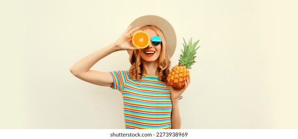 Summer portrait of happy smiling young woman with pineapple and slice of orange, fresh tropical juicy fruits, wearing straw hat, sunglasses on white background - Powered by Shutterstock