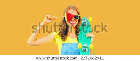 Summer portrait of happy smiling young woman with lollipop or ice cream shaped slice of watermelon on orange background