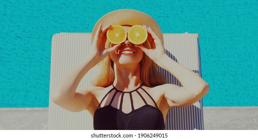 Summer Portrait Of Woman Covering Her Eyes With Slices Of Orange Wearing A Straw Hat On Deck Chair On A Pool Background