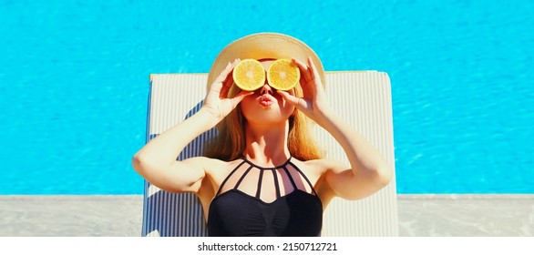 Summer Portrait Of Woman Covering Her Eyes With Fresh Slices Of Orange Lying On Deck Chair On Pool Background