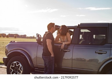 Summer Portraits Of A Caucasian Couple In Their 40s Going On A Road Trip. The Woman Is Sitting In The Car And Leaning Out The Car Window And Chatting With Her Husband Who Is Standing Outside The Car.