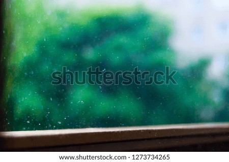 Summer rain raindrops falling down on wooden painted handle of balcony railings on blurred trees background