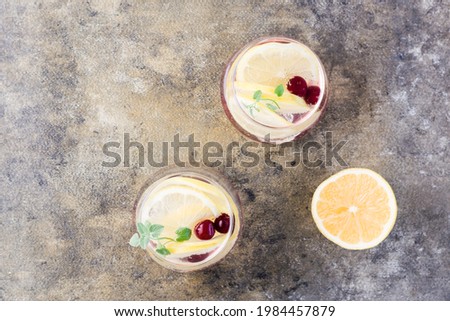 Summer refreshing cold cocktail with lemon, lemon balm and cherry - hard seltzer in glasses on the table .  Top view