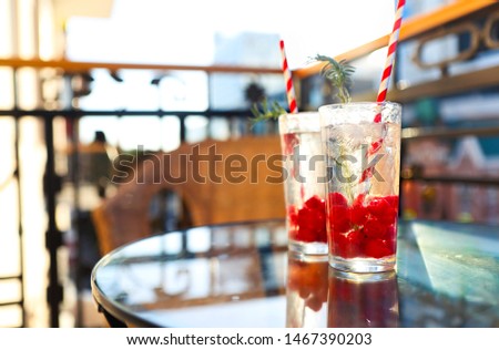 Summer refreshing lemonade with rasberry on a balcony of terrace, paper straw on the glasses. Sunset