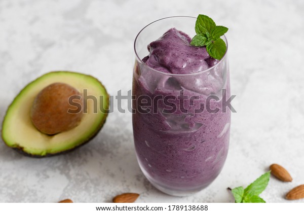 Summer refreshing smoothie with avocado,\
blueberries and almond milk in a glass glass on a light background.\
Diet cocktail, keto\
recipes.