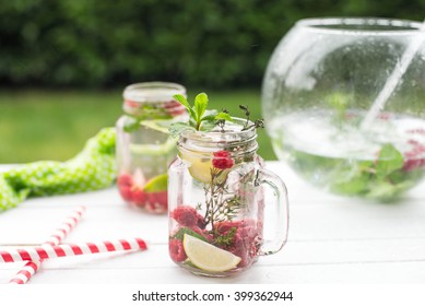 Summer Refreshment Drink. Water With Raspberry, Lime, Ice, Mint And Thyme On Rustic Background. Pink Detox.