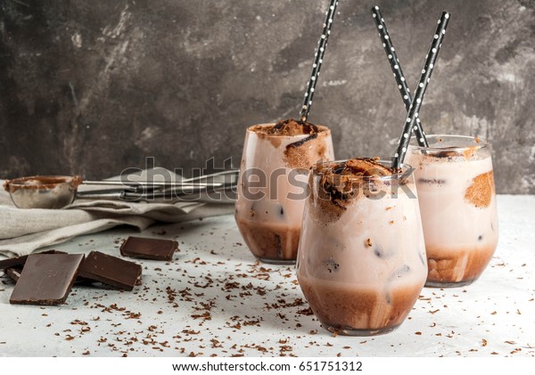Summer refreshment drinks. Chilled iced chocolate\
cocoa. With scoop of chocolate ice cream, chocolate powder and ice.\
In glasses, with tubes for drinking. White concrete table. Copy\
space